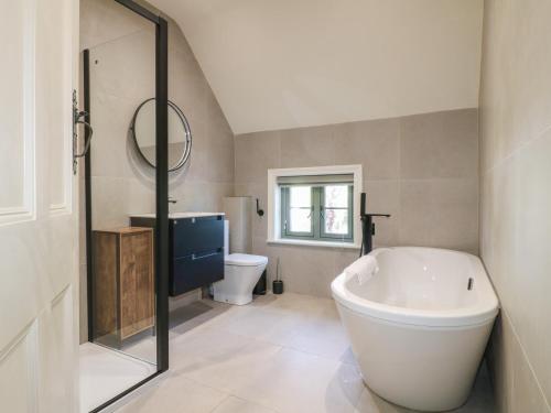 a bathroom with a large tub and a toilet at Gardeners Cottage in Oakham