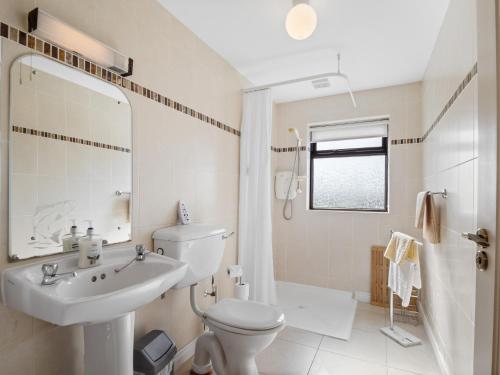 a white bathroom with a toilet and a sink at Little Tara, Ballyconneely in Ballyconneely
