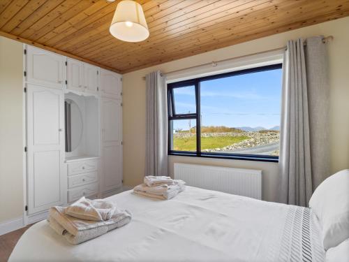 a bedroom with a bed and a large window at Little Tara, Ballyconneely in Ballyconneely