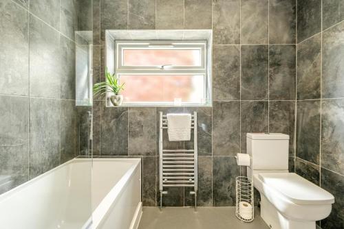 a bathroom with a tub and a toilet and a window at 4 Bed in Bideford oc-76452 in Parkham