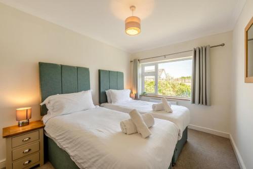 two twin beds in a bedroom with a window at 4 Bed in Bideford oc-76452 in Parkham