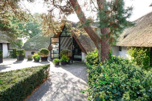 a house with a thatched roof and a tree at Mooirivier in Dalfsen