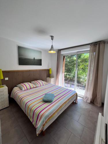 a bedroom with a bed and a large window at La Villa Belle in Biscarrosse