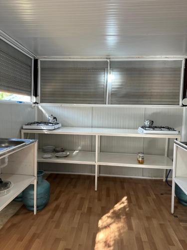 a kitchen with white shelves and a table at Adrasan Camping in Kumluca