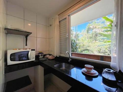 a kitchen with a microwave and a sink and a window at Flat Salto Dagua Penedo in Penedo
