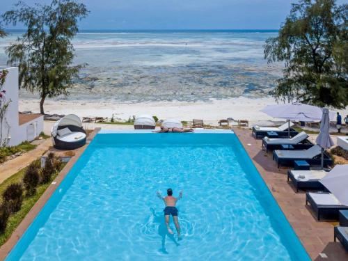 a man in a swimming pool next to a beach at Nungwi Dreams by Mantis in Nungwi