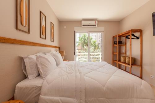 a bedroom with a white bed and a window at Almaê Pousada in Matinhos