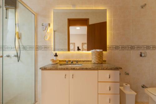 a bathroom with a sink and a shower with a mirror at Almaê Pousada in Matinhos