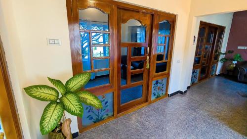 a hallway with wooden doors and a potted plant at Cloud Crest Homestay in Ooty