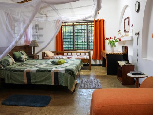a bedroom with a bed and a couch and a window at Tradewinds Lodge in Diani Beach