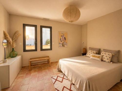 a bedroom with a large bed and two windows at Villa familiale avec piscine hyper centre in Valras-Plage