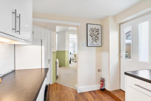 a kitchen with white cabinets and black counter tops at Spacious 2-Bed Eastbourne Retreat in Eastbourne