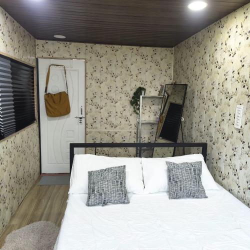 a bedroom with a white bed and a wall with wallpaper at OrchardNest in Moinabad