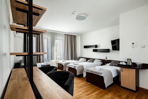 a hotel room with three beds and a living room at Restauracja Sonata in Zwierzyniec