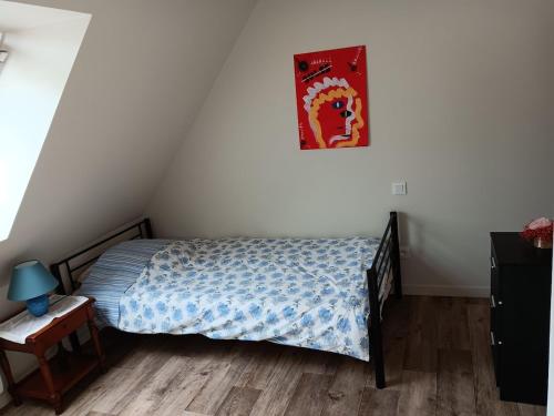 a bedroom with a bed and a picture on the wall at L'Authentique in Mouzay