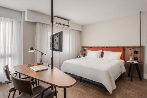 a bedroom with a bed and a table and a desk at Intercity Porto Alegre Praia de Belas in Porto Alegre