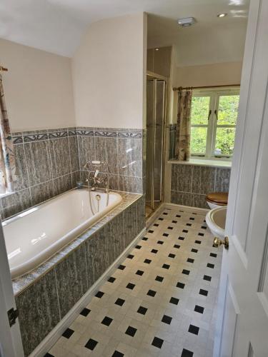 a bathroom with a tub and a tiled floor at The Martins B&B in Chelsworth