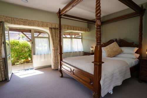 a bedroom with a four poster bed and a balcony at Asquith Hall Hotel & Spa Scarborough in Scarborough