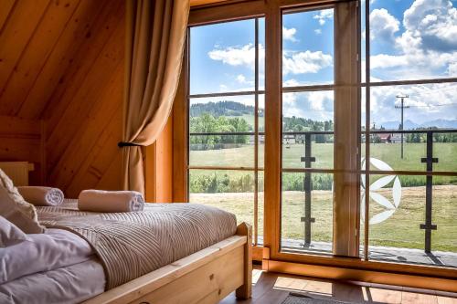 a bedroom with a bed and a large window at Jagodowa Osada - domki z balią z hydromasażem blisko term in Dzianisz