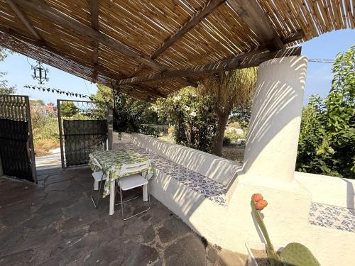 a patio with a table and a wooden pergola at House La Pennata - sea view in Malfa