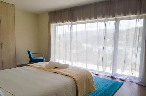 a bedroom with a bed and a large window at ERMAL HOUSE in Braga