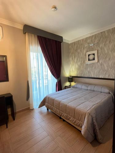 a bedroom with a bed and a large window at Hotel Hermitage in Qualiano