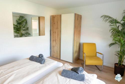 a bedroom with two beds and a yellow chair at Aviva ANKERPLATZ - Familien-Oase mit Gartenterrasse und 2 Schlafzimmern in Bodman-Ludwigshafen