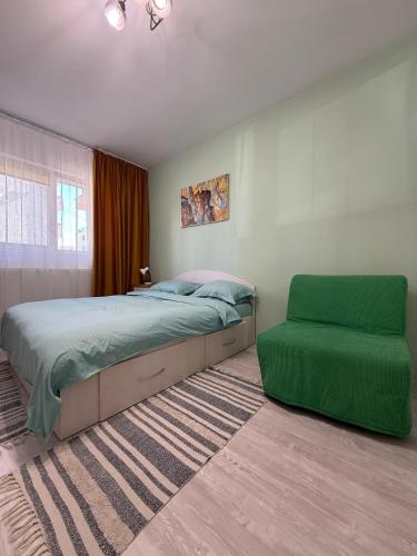 ein Schlafzimmer mit einem Bett und einem grünen Stuhl in der Unterkunft Mary's Studio in Ipoteşti