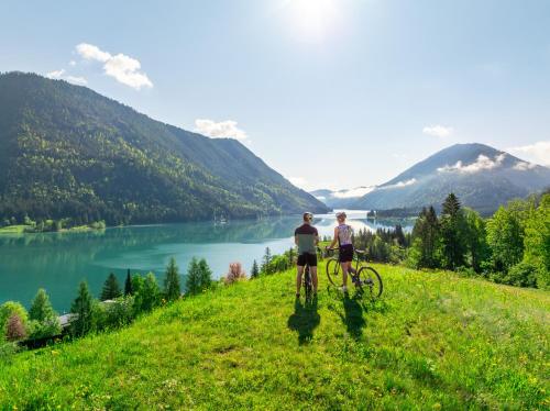 two people riding bikes on a grassy hill overlooking a lake at Haus Stampfer in Weissensee