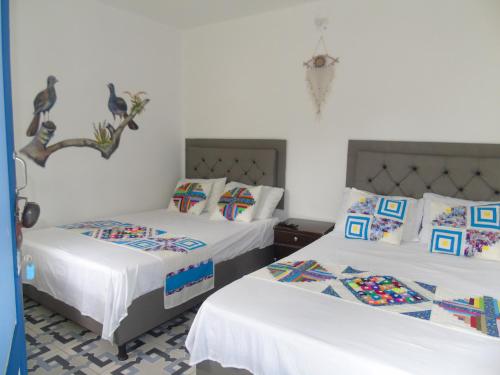 two twin beds in a room with white walls at Vista Farallones Hostel in Jardin