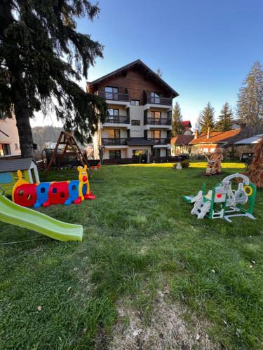 a group of playground equipment in the grass in front of a building at Garden Apart in Predeal