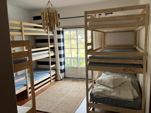 a room with four bunk beds and a window at Santa Cruz Surf House by Stoke Travel in A dos Cunhados
