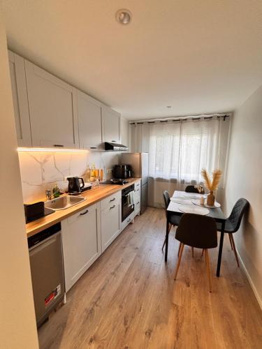 a kitchen with white cabinets and a table and a dining room at Veriora külaliskorter in Veriora