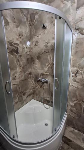 a shower in a bathroom with a stone wall at Vinnytsia City Center Guest House in Vinnytsya