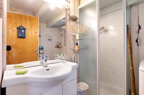a white bathroom with a sink and a shower at Petite Villa Mitoyenne Dans Pinède in Lacanau-Océan