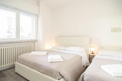 a white bedroom with two beds with towels on them at Appartamenti Federica 12T in Milano Marittima