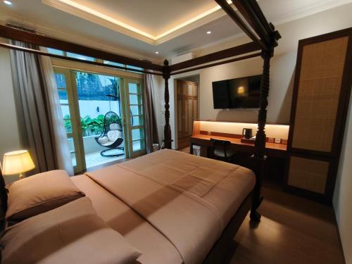 a bedroom with a bed and a desk and a television at Dalem Kamulyan Kraton in Timuran