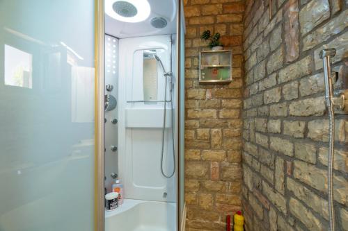 a bathroom with a shower and a brick wall at Polilimnio Foteini's Mini Castle in Metamórfosis