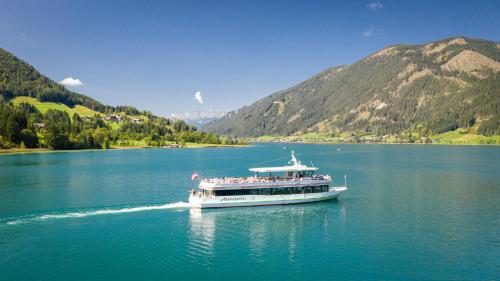 a boat on a lake with mountains in the background at Haus Stampfer in Weissensee