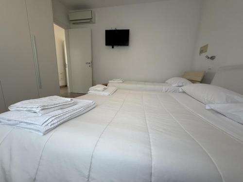 a white room with two beds and a flat screen tv at Appartamenti Federica 12P in Milano Marittima