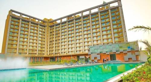 a large hotel with a swimming pool in front of it at Weekend address in Surat