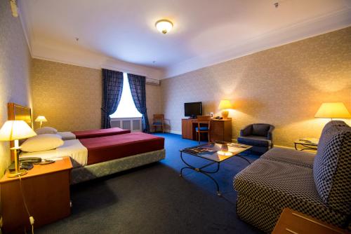 a hotel room with a bed and a couch at Grand Hotel Ukraine in Dnipro