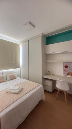 a bedroom with a white bed and a desk at Flat 707 Moderno e Espaçoso, próximo ao Praia Clube in Uberlândia