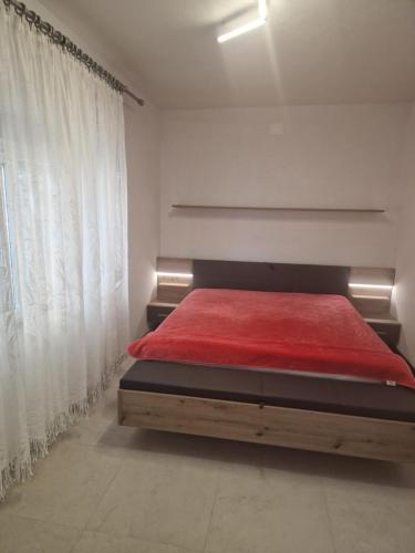 a bedroom with a bed with a red blanket at Guest House Perla in Sveti Juraj