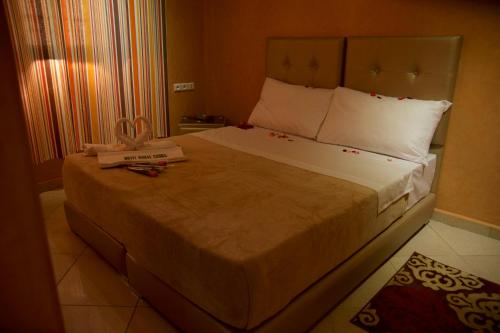 a bedroom with a large bed with a large white bedspread at Hotel Rimal Sahara in Laayoune
