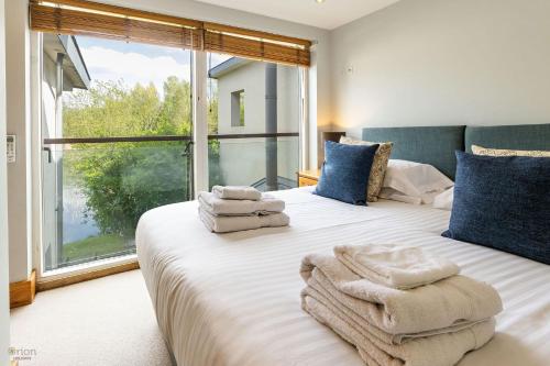 a bedroom with a large bed with towels on it at Clearwater 67, Ortolan Villa in Somerford Keynes