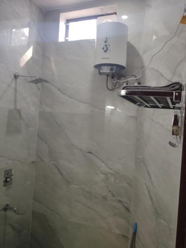 a bathroom with a shower with a light on the wall at The Whistling Pine Homestay With Natural Swimming Pool in Lansdowne