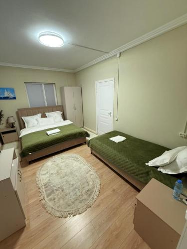 a bedroom with two beds and a rug at Duman House in Almaty