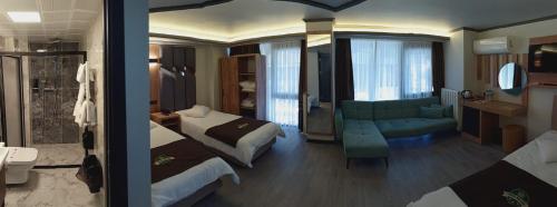 ein Hotelzimmer mit zwei Betten und einem grünen Sofa in der Unterkunft Hotel Milano in Rize