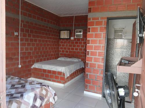 a brick room with a bed in a brick wall at Chalé 01 cantinho do ceu in Santo Amaro